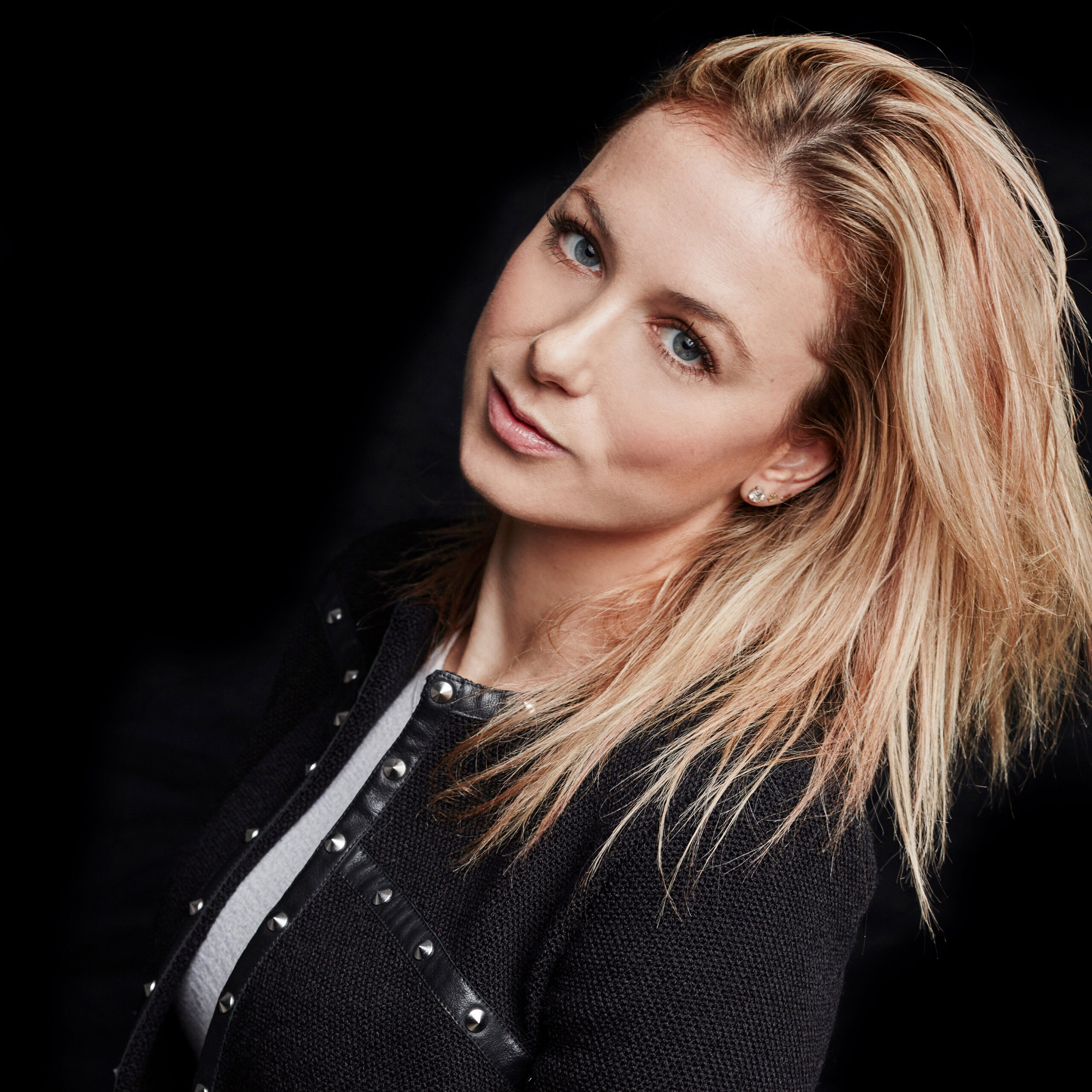 Iliza Shlesinger wearing black in front of a black background.