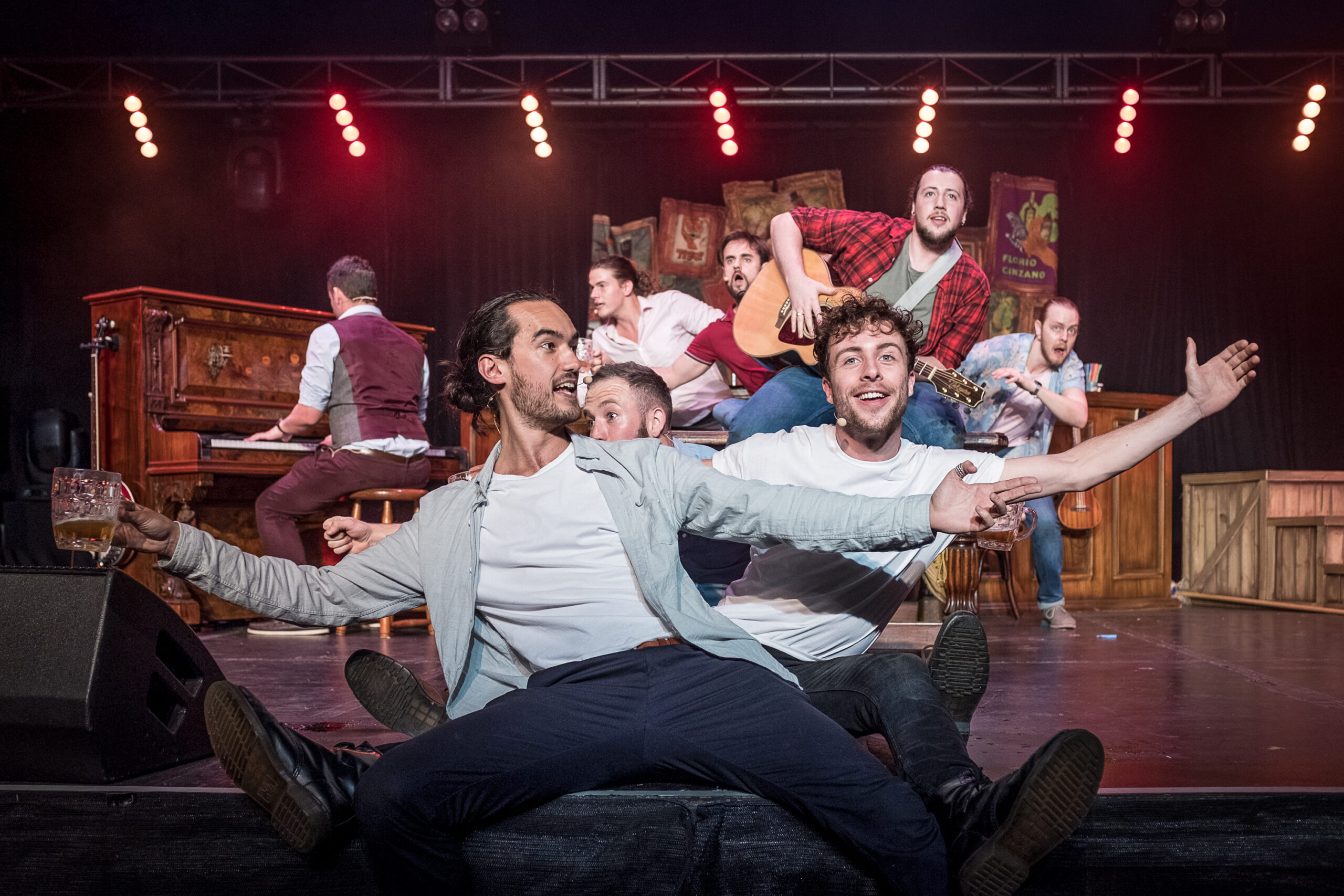 The cast of Choir of Man lined up and singing with beers in hand.