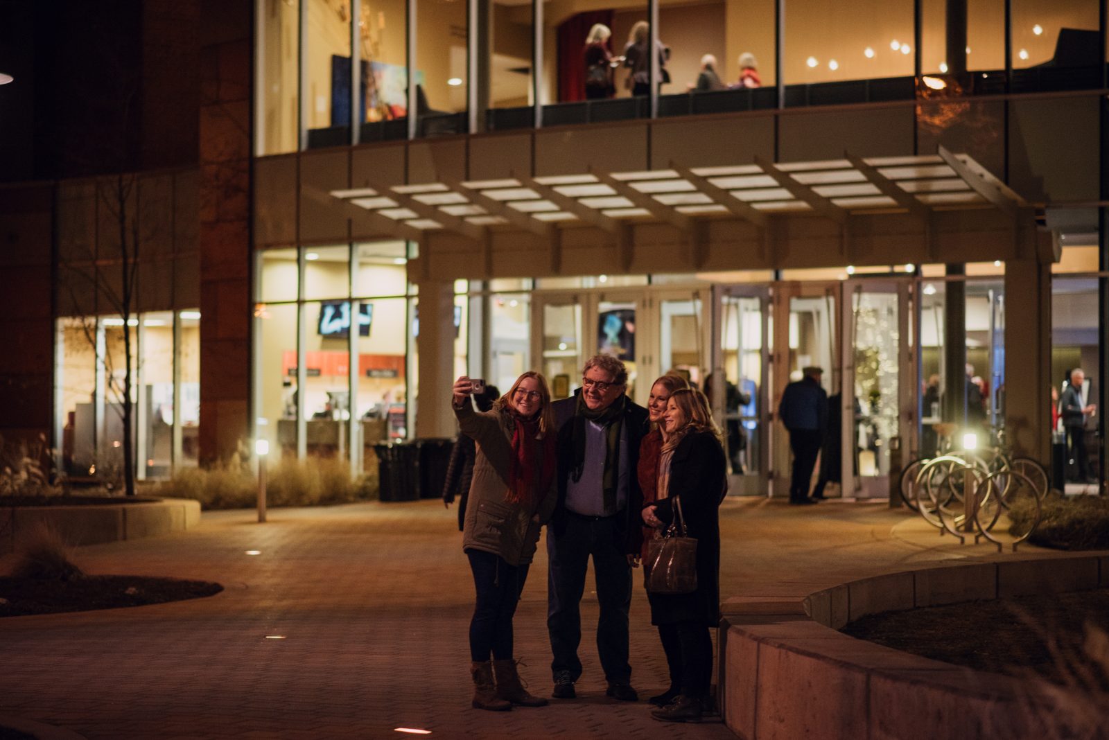 A family taking a selfie outside a fully lit Lincoln Center.