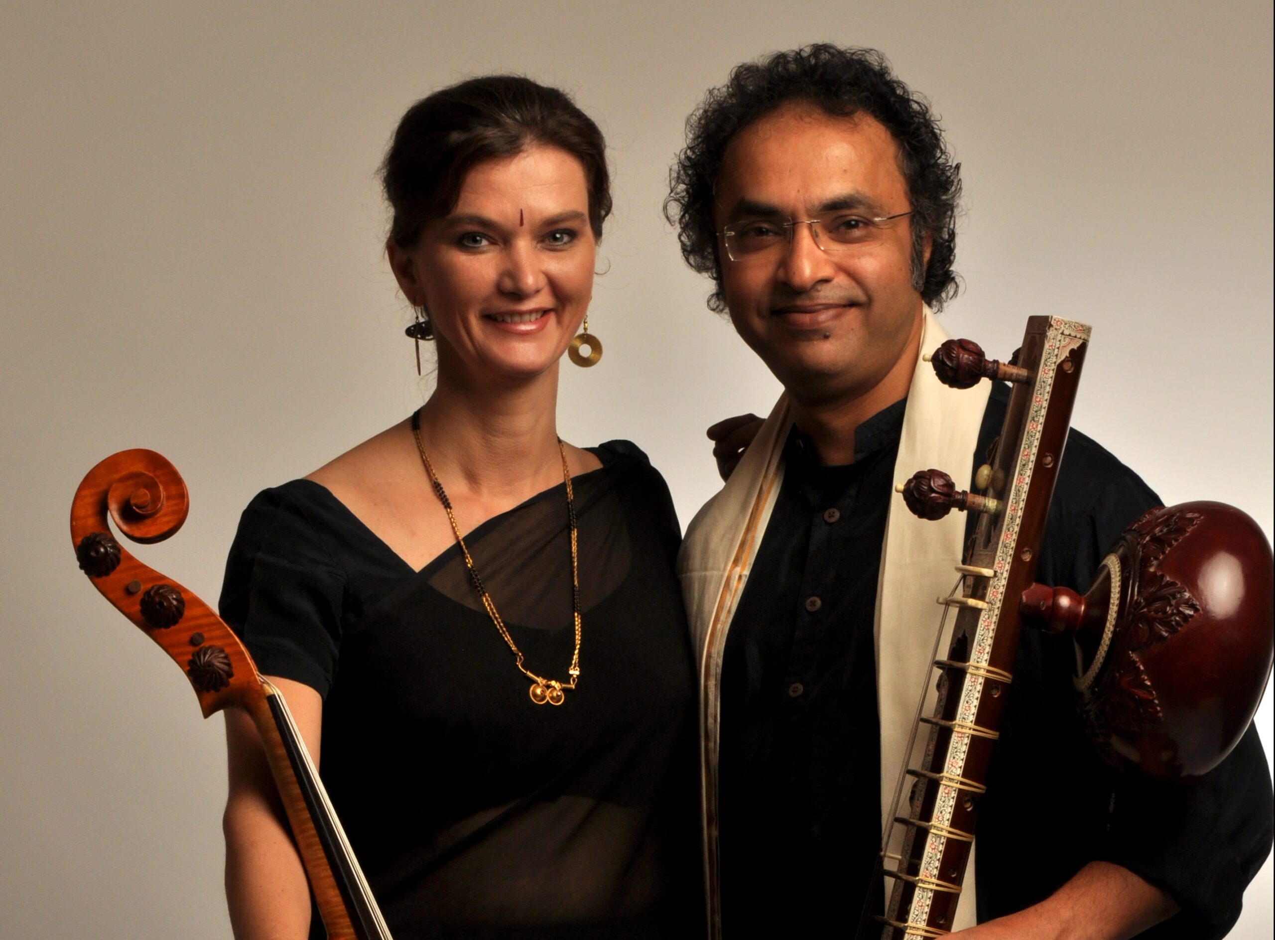 A photo of Shubhendra Rao and Saskia Rao-de Haas holding their instrumetns and smiling.