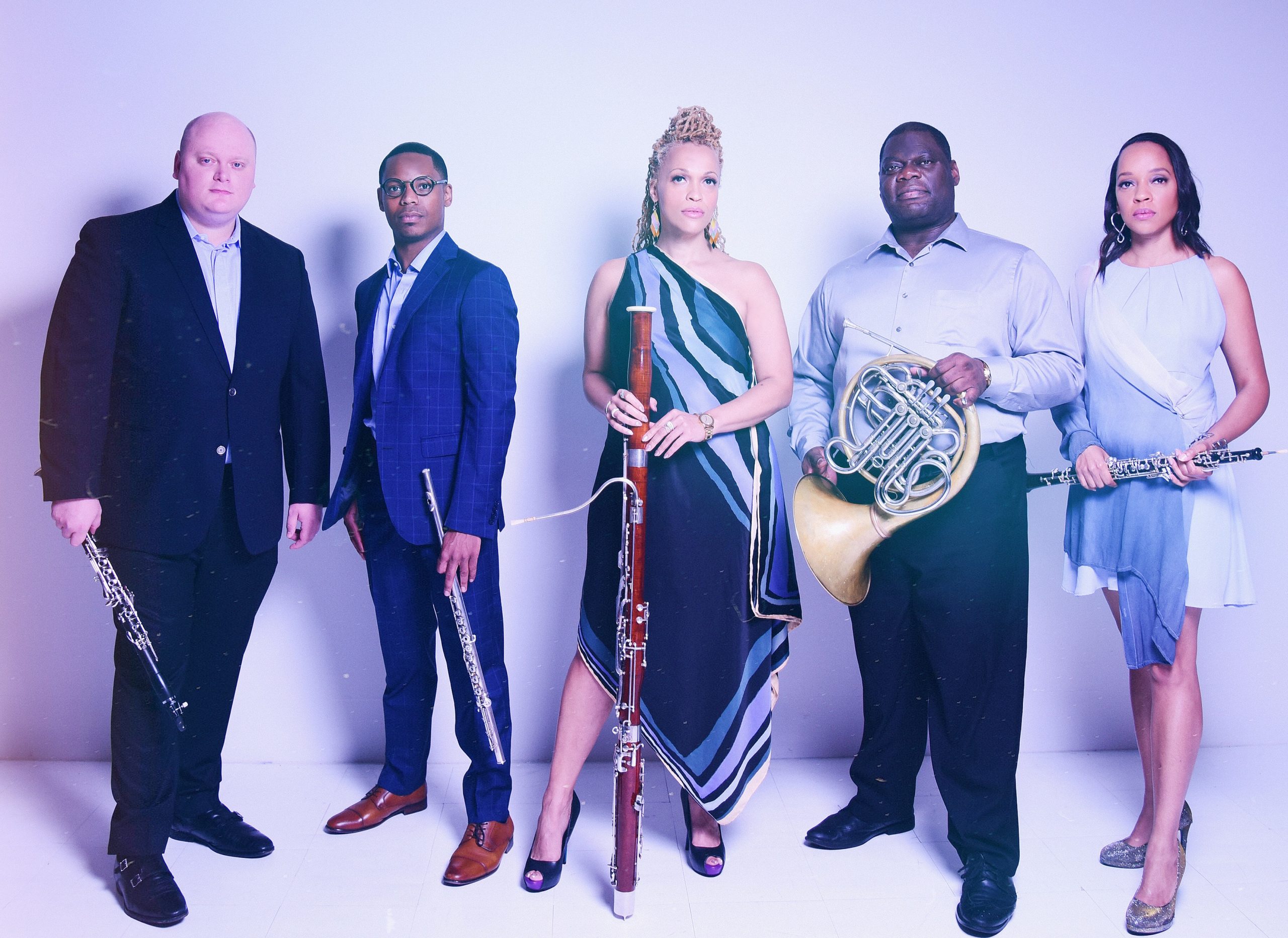 The five members of Imani Winds standing with their instruments looking serious.