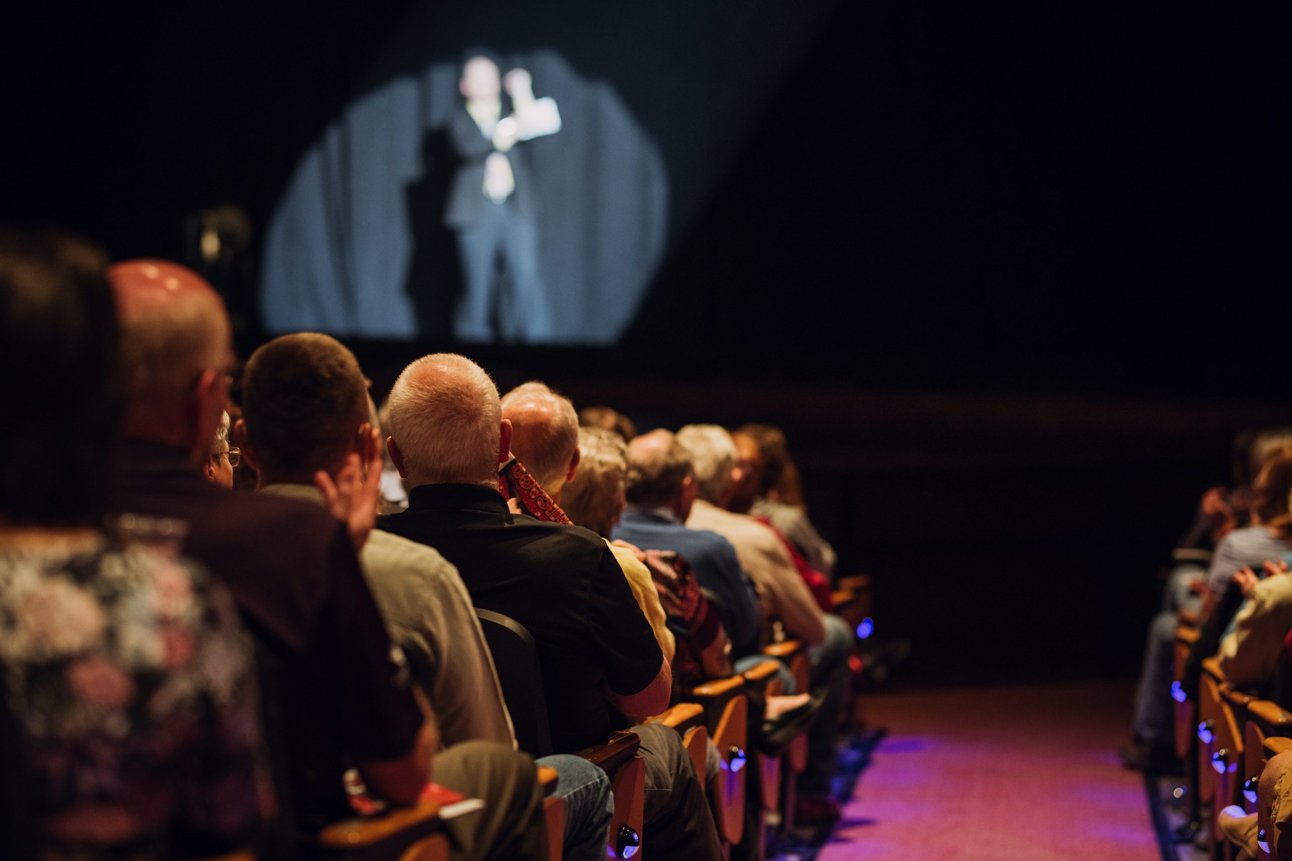 A photo of Jack Rogers in a spotlight in front of a crowd in The Lincoln Center Performance Hall.