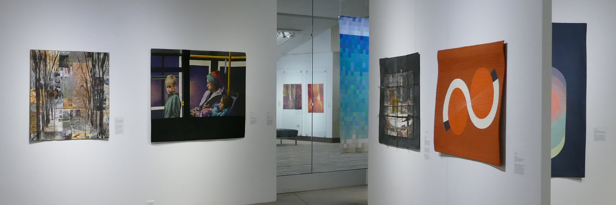 Art quilts in The Lincoln Center Art Gallery. The quilts on display in the lobby are visible in the middle of the frame.