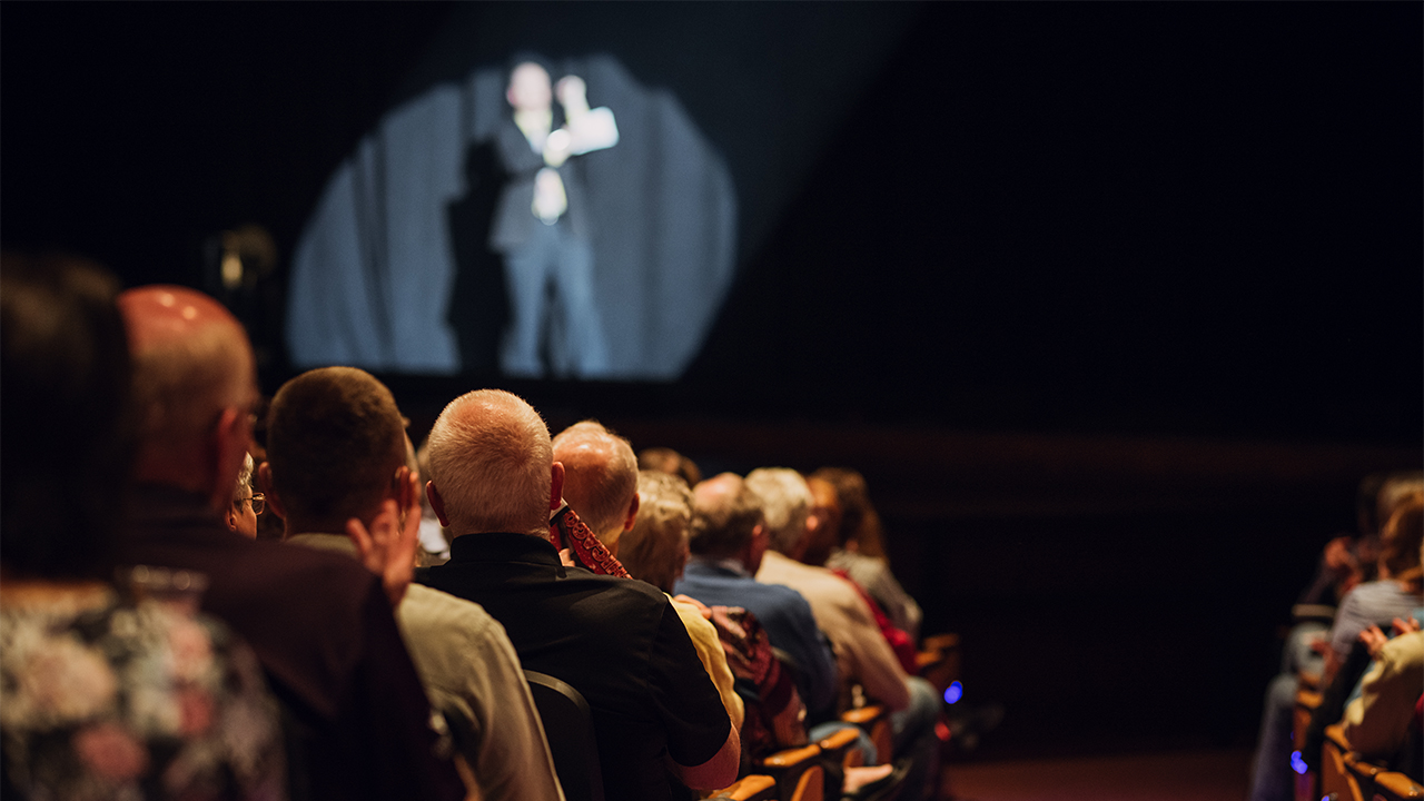 Audience applauds man on stage in the Performance Hall.