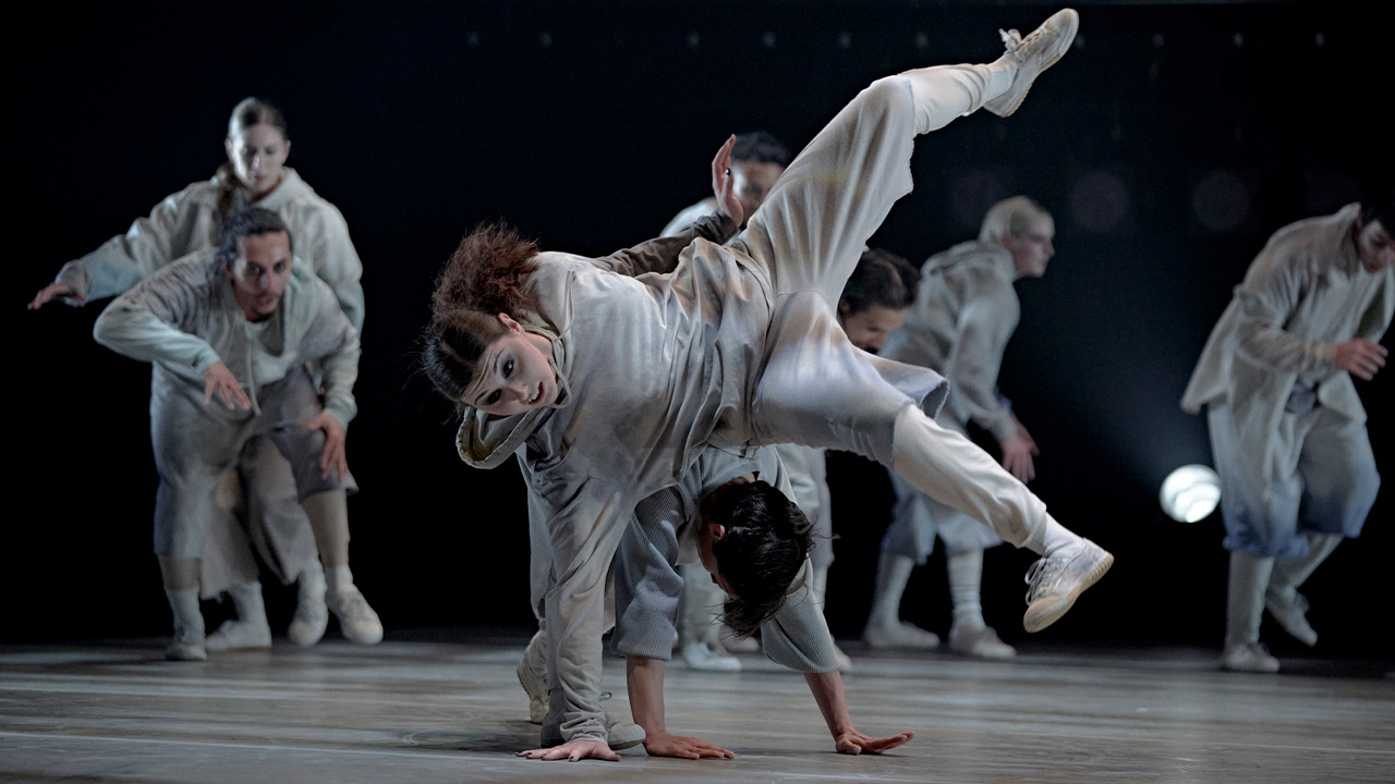 A group breakdancing in grey clothes