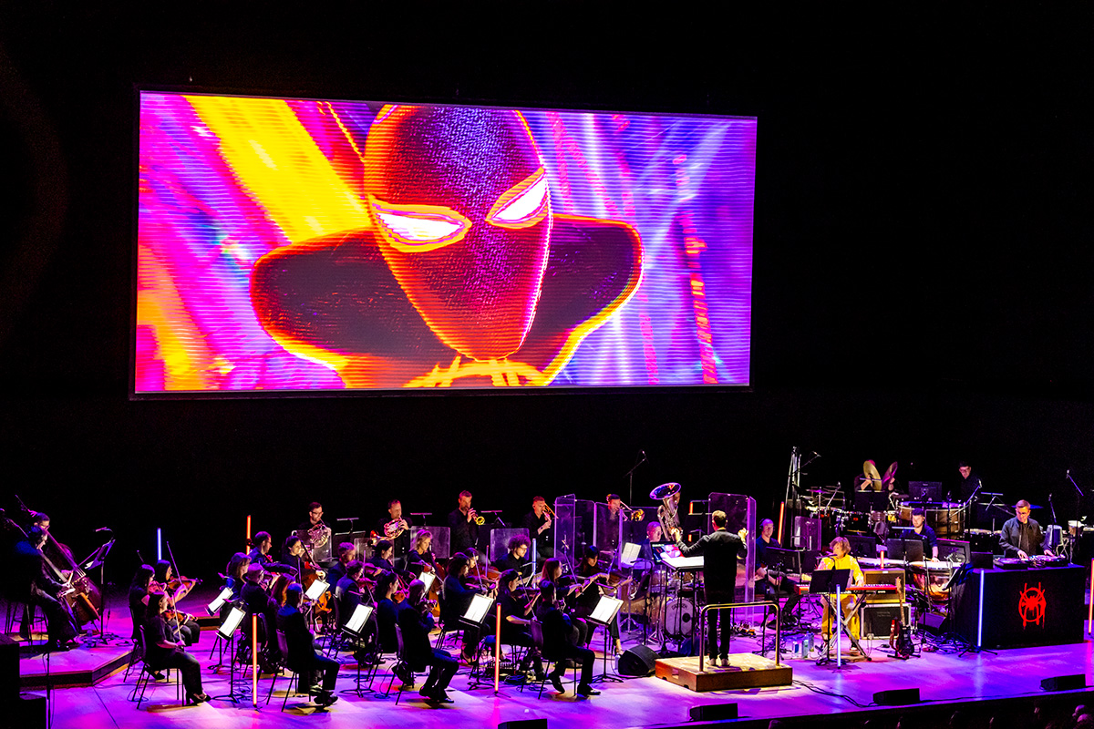 Spider-Man playing on a movie screen with an orchestra below.