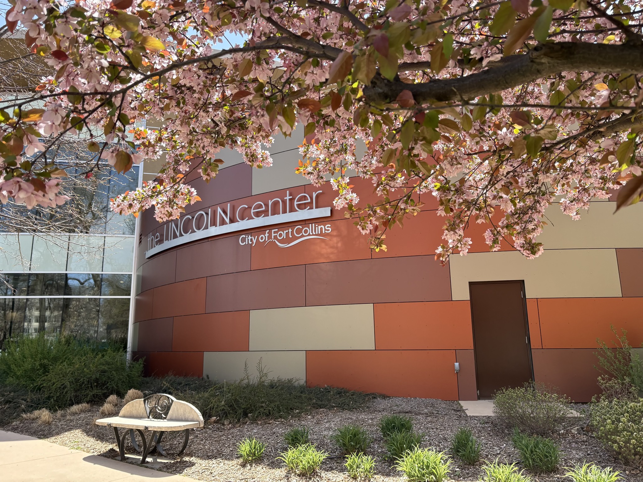 A flowering tree branch hangs over The Lincoln Center sign.