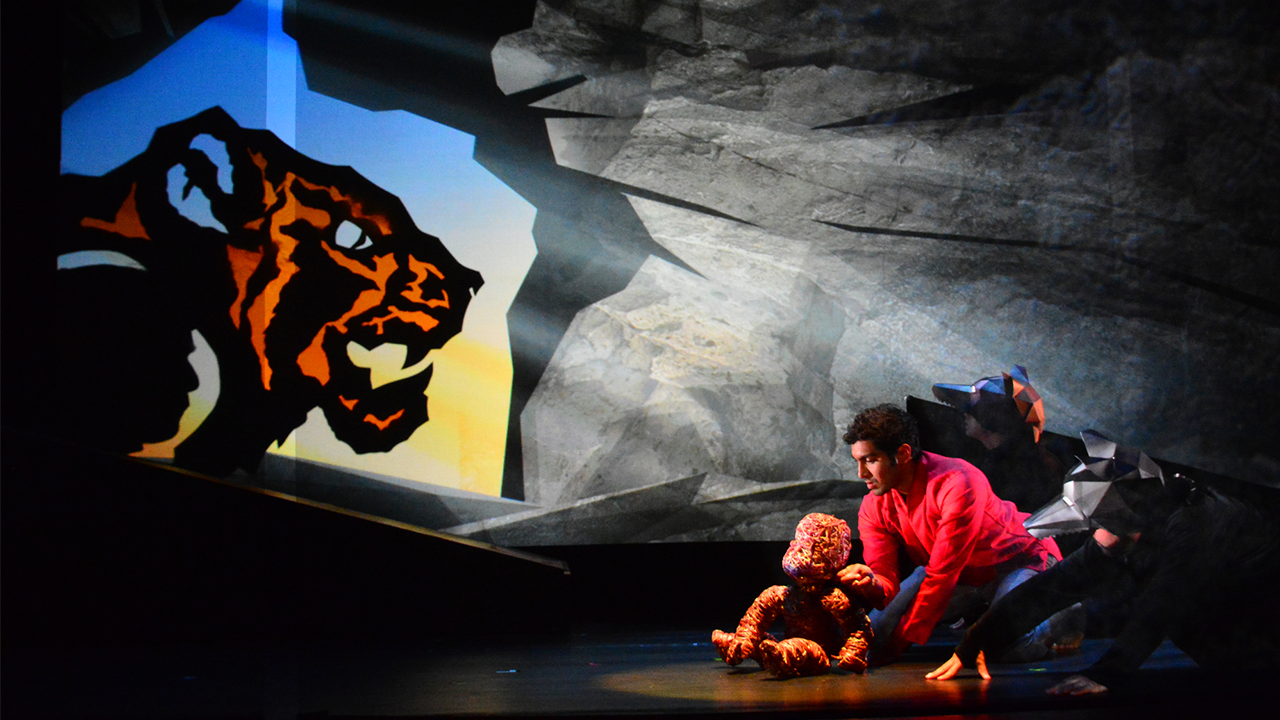 Shere Kahn and Mowgli puppets and puppeteers performing on stage.